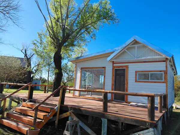 Cabaña blanca con deck de madera entre los árboles