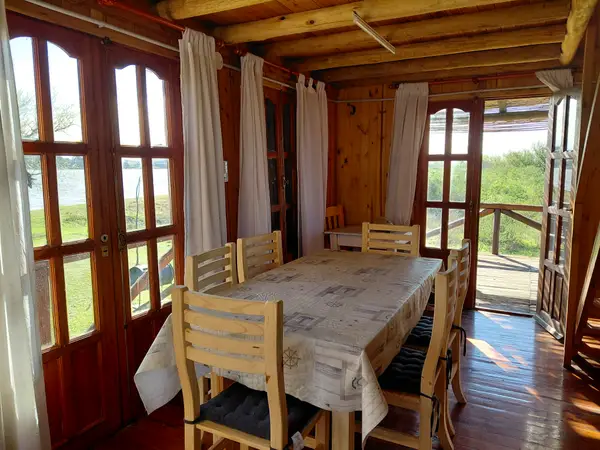 Comedor de la cabaña con mesa para seis y puertas vidriadas al río