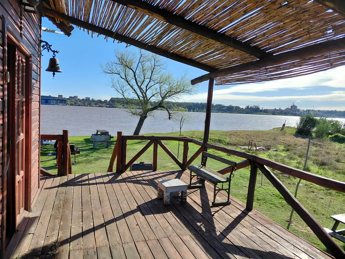 Deck de la cabaña con banco de madera y vista al río Paraná