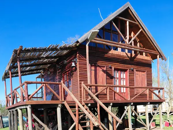 Cabaña de madera sobre pilotes con escalera y galería