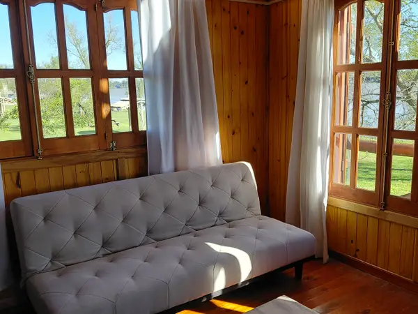 Living con sillón y ventanales de madera
