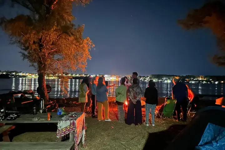 Noche en la isla con fogón y las luces de la ciudad del otro lado del río