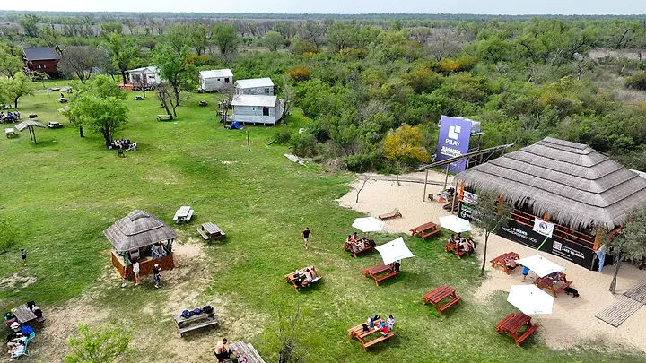 El parador con mesas y sombrillas, y el camping al fondo